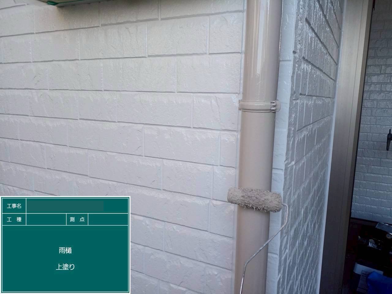 ベージュの塗料で上塗り仕上げ中の雨樋